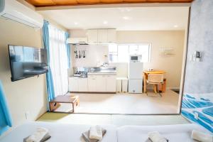 a small kitchen with white cabinets and a table at Court Ada -1min to Araiyakushi-mae Station, 9min train to Shinjuku- 新井薬師前駅徒歩50秒 in Tokyo