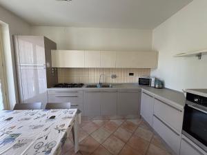 a kitchen with white cabinets and a table and a sink at Casa Emma in Torre Pellice