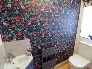 a bathroom with a toilet and a wallpaper with flowers at The Barn in Redditch +21 photos