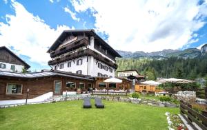 ein großes Gebäude mit einem Rasen davor in der Unterkunft Wellness Hotel Bladen in Sappada