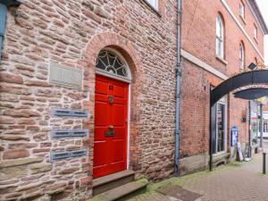 a red door on the side of a brick building at Stylish Town Apartment in Ross on Wye
