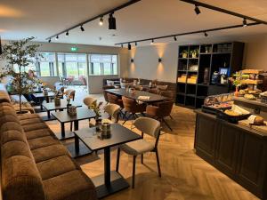 a restaurant with tables and chairs in a room at Hotel het Uilenbos in De Koog