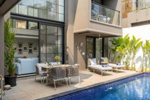 a patio with a table and chairs next to a pool at Lindsay Manor Santo Sovrano 4BHK Heated Pool in Vagator