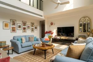 a living room with blue couches and a tv at Lindsay Manor Santo Sovrano 4BHK Heated Pool in Vagator