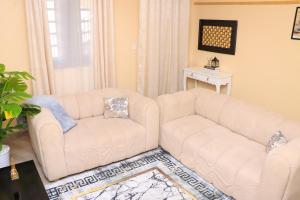 a living room with two white couches and a table at Gee Homes and Stays in Nyahururu