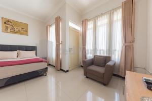a bedroom with a bed and a chair and a window at Wisma Brata 2 Mitra RedDoorz in Nyomolong