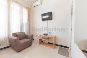 a living room with a chair and a table at Wisma Brata 2 Mitra RedDoorz in Nyomolong +17 photos