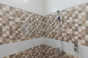 a shower with brown and white tiles in a bathroom at Wisma Brata 2 Mitra RedDoorz in Nyomolong