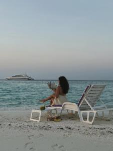 a woman sitting on a chair on the beach at RITRELLA FLOATING HOTEL&YACHT - FREE beach access daily - Full board meal plan in Male City