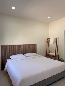 a bedroom with a large white bed and a chair at Wanwichai Room in Ban Lam Ru (1)