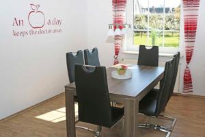 a dining room table with black chairs and an apple sign at Ferienhaus Minners in Jork