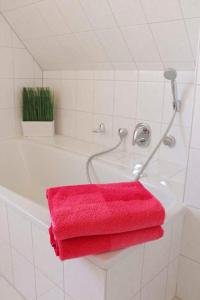 a bathroom with a red towel on the side of a tub at Ferienhaus Minners in Jork +4 photos