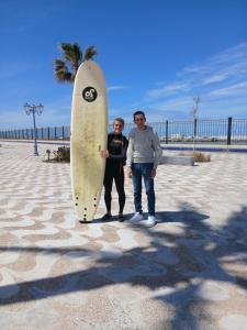 a man and a woman standing next to a surfboard at Casa Youssef 1 in Asilah