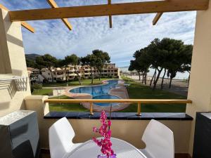 ein Balkon mit Tisch und Stühlen und ein Swimmingpool in der Unterkunft Punta Atico in Alcanar