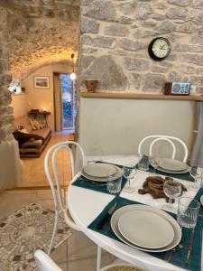 a table with chairs and a clock on a stone wall at Gîte de charme au pied du Château de Brissac in Brissac
