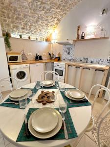 a kitchen with a white table with plates and chairs at Gîte de charme au pied du Château de Brissac in Brissac