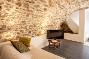 a living room with a couch and a stone wall at Maison de l'Orb in Cessenon