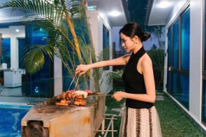 a woman is cooking meat on a grill at New Sky Light Villa in Dong Hoi