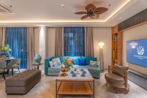 a living room with a blue couch and a tv at Solaro Hotel & Spa Phu Quoc - Sunset Town Seaview & Fireworks in Phú Quốc