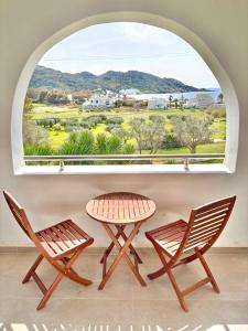 two chairs and a table in front of a window at Marcos Beach in Mylopotas