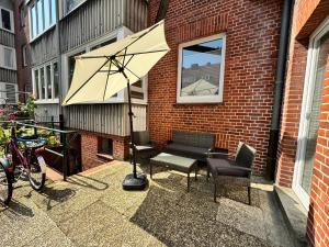 a bench and an umbrella next to a brick building at Altstadt Ankerplatz - zentral, modern, WLAN - perfekt für Paare in Emden