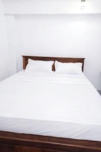 a bed with white sheets and two pillows at Robert's-stay in Katunayaka