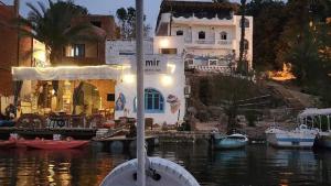 a white house with a marina with boats in the water at Amir Nile Guest house in Aswan