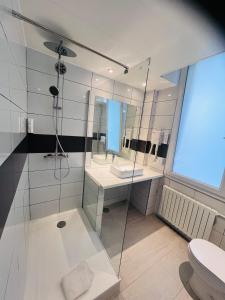 a bathroom with a glass shower and a toilet at Hôtel De La Cathédrale in Reims