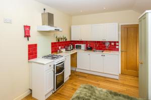 a kitchen with white cabinets and red tiles at Firhurst in Aboyne
