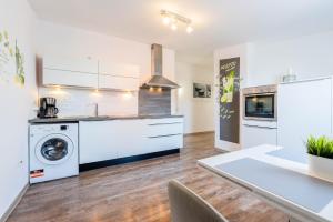 eine Küche mit weißen Schränken und einer Waschmaschine und einem Trockner in der Unterkunft Hafencity Apartments in Tönning