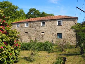 an old stone building in a garden with flowers at Quinta da Coutada - AgroTurismo in Arcos de Valdevez