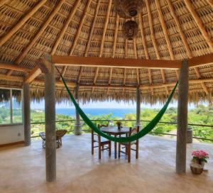 a room with a hammock in a straw hut at Villa Luna de Miel in Mazunte