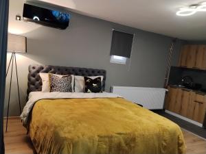 a bedroom with a large bed with a yellow blanket at Zen Lux in Zaječar