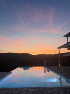 a swimming pool with a sunset in the background at Villa Magiko in Poros