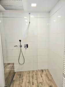 a shower with a hose in a white tiled bathroom at Vila Vannet II in Liptovský Mikuláš +25 photos