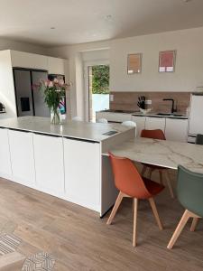 a kitchen with white cabinets and a table and chairs at La Maison De Parrain in Kerlouan