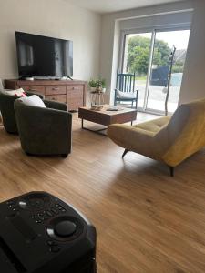a living room with couches and a tv at La Maison De Parrain in Kerlouan