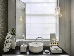 a bathroom with a tub and a sink and a window at Fable Auckland, MGallery in Auckland