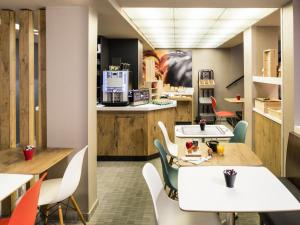 a restaurant with tables and chairs and a kitchen at ibis Clichy Centre Mairie in Clichy