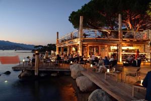 a group of people sitting at a restaurant on a dock at VILLA LE CORAIL ROUGE CORSE in Lecci