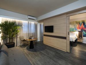 a hotel room with a bed and a table and a tv at Novotel Itajai Navegantes in Itajaí