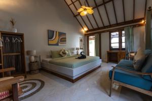 a bedroom with a bed and a chair in a room at The Swan Villa in Gili Trawangan