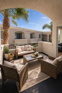 a patio with wicker furniture and a palm tree at Modern 1 & 2 Bedroom Apartments Near Venice & MDR with Pool Gym & Cinema in Los Angeles