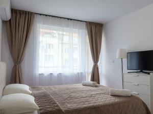 a bedroom with a bed and a tv and a window at Shazam Apartment Central, Stylish & Cozy near AUBG in Blagoevgrad