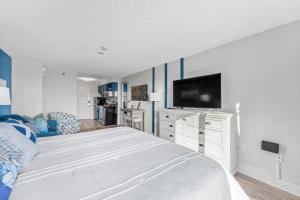 a bedroom with a white bed and a tv at Beach View Condo in Myrtle Beach