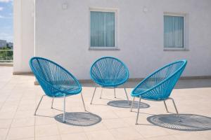 three blue chairs sitting on top of a tile floor at Hotiday Rooms Torre Lapillo in Torre Lapillo