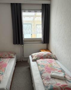 two beds in a room with a window at Penzion Borováček in Borová Lada
