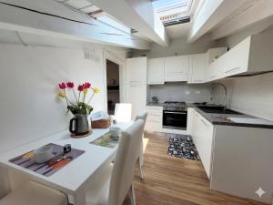 a kitchen with white cabinets and a white table and chairs at Light on Lake Iseo in Clusane sul Lago
