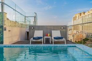 a rooftop pool with two chairs and a table on a building at Solaro Hotel & Spa Phu Quoc - Sunset Town Seaview & Fireworks in Phú Quốc
