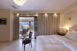 a bedroom with a bed and a chair and a balcony at Villa Visanty with Private Pool & Access to Beach in Aigosthena +44 photos